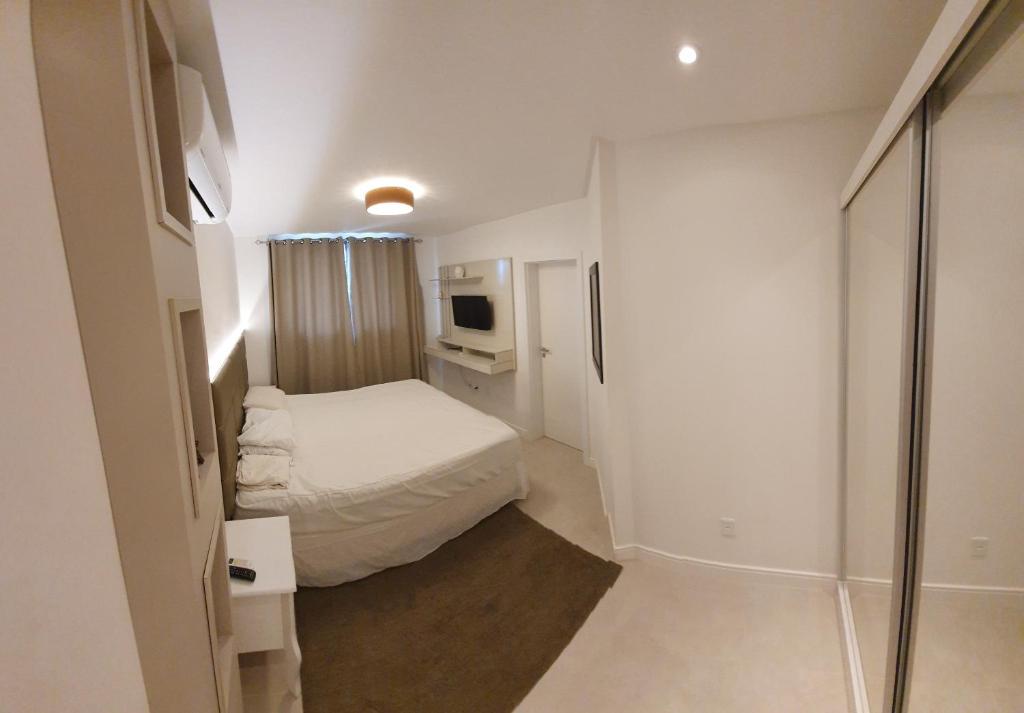 Habitación blanca pequeña con cama y TV en Apartamento Residencial Bordô amplo 3 quartos próximo à praia, en Itapema