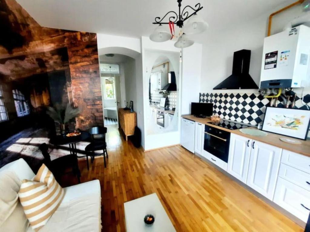 a kitchen and living room with white cabinets and wooden floors at One bedroom by the Park Old Town Timisoara in Timişoara