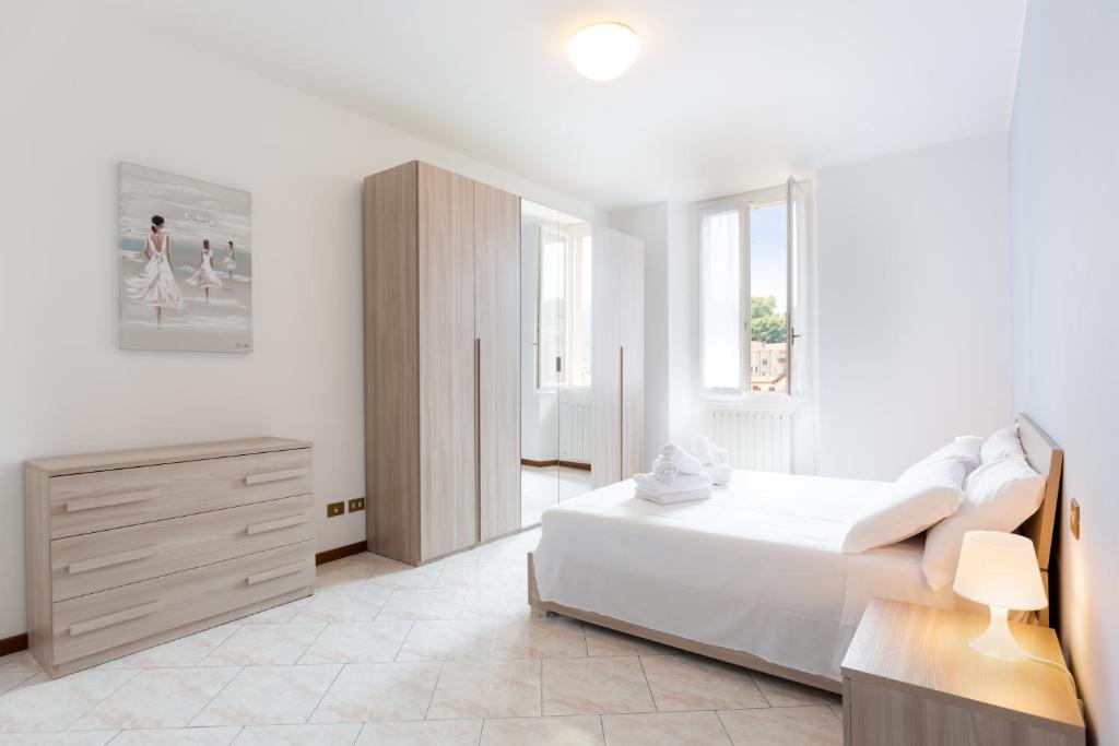 a white bedroom with a bed and a dresser at Carola's place - by Relais Di Giada in Como