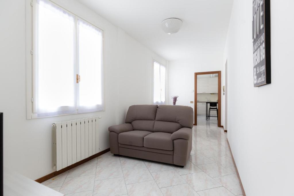 a living room with a brown chair and windows at Carola's place - by Relais Di Giada in Como