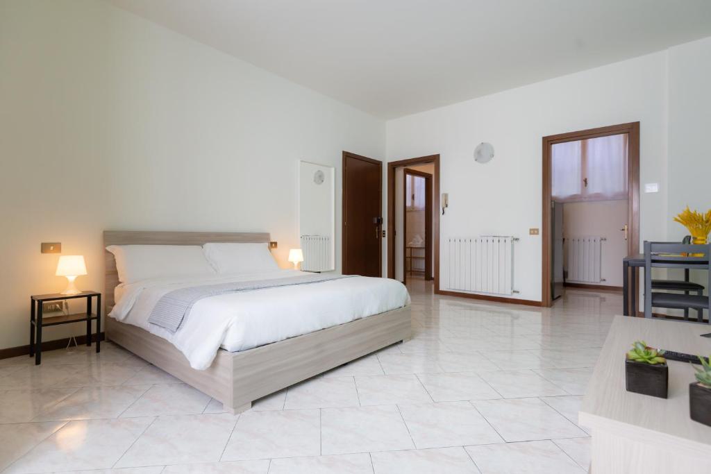 a white bedroom with a large bed and a table at Carola's place - by Relais Di Giada in Como