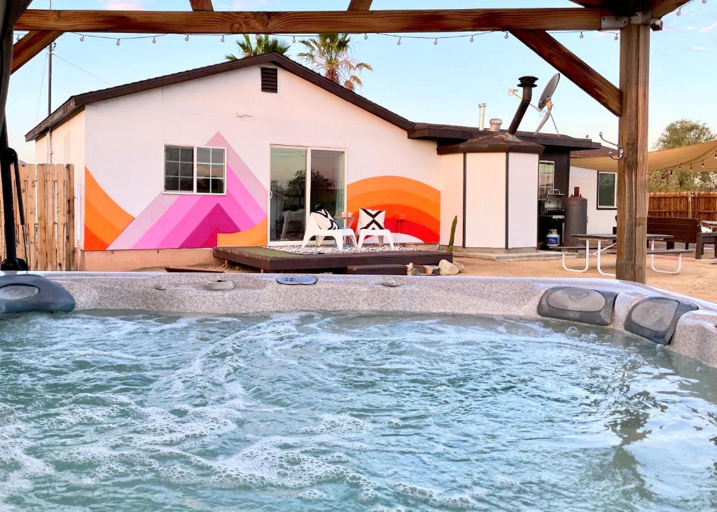 a house with a large swimming pool in front of it at Twin Palms Desert Getaway - Jacuzzi, Fire pit, Meditation room & more in Joshua Tree