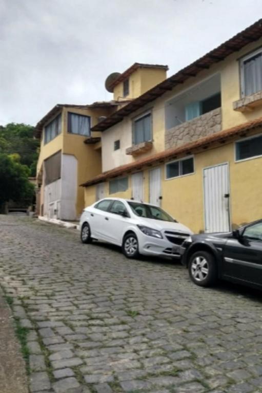 twee auto's geparkeerd voor een gebouw bij Antonia Hospedaria 2 in Búzios