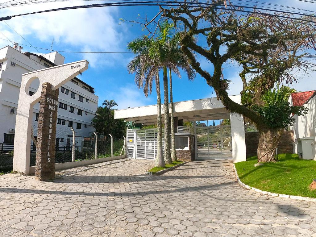a street with palm trees and a building at 124 - Apartamento 3 dormitórios condomínio fechado in Bombinhas