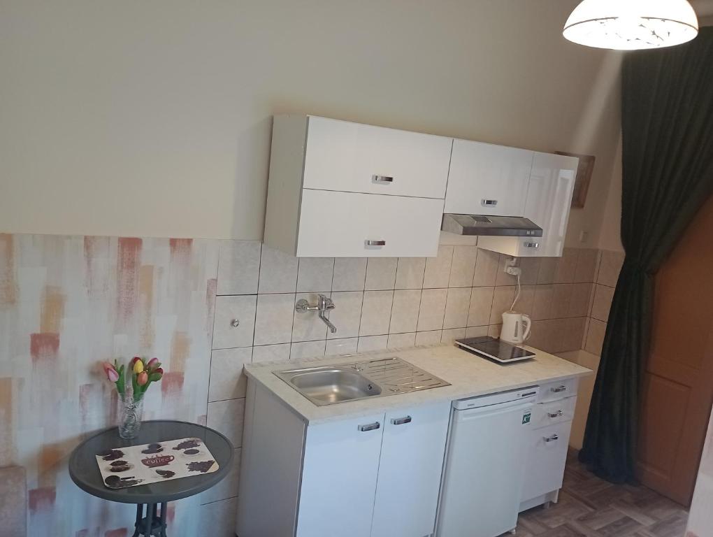 uma pequena cozinha com armários brancos e um lavatório em Kawalerka. em Przemyśl