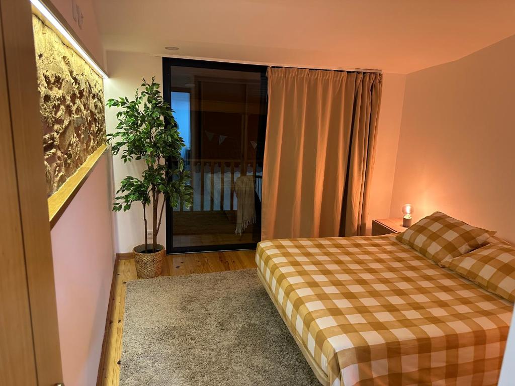 um quarto com uma cama e uma janela com uma planta em Casa d'avó Coragem em Seia
