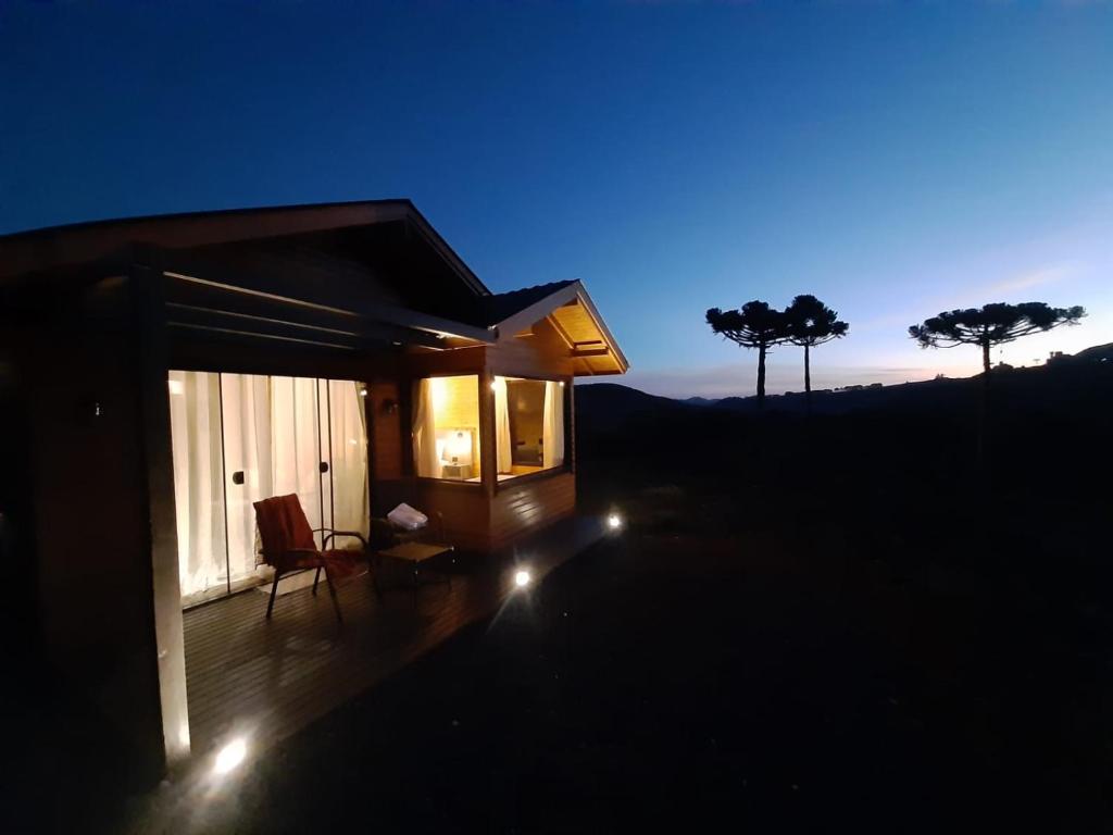 uma pequena casa com luzes num deque à noite em Pousada Recanto da Cascata - Cabana Liquidambar em São Joaquim