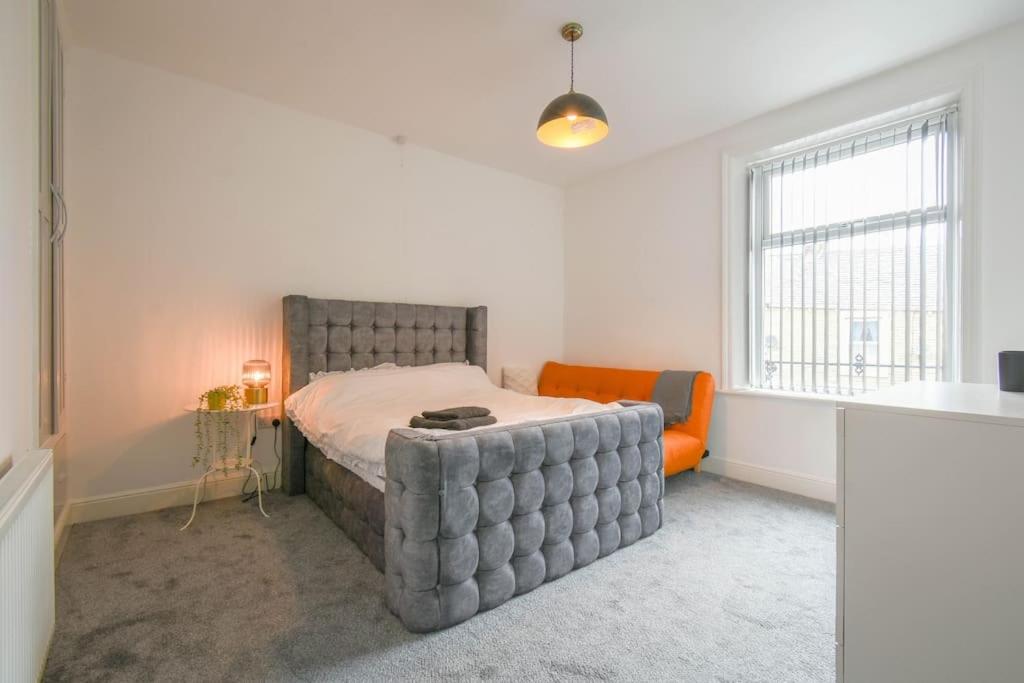 a bedroom with a bed and an orange chair at Home in the Heart of Accrington in Church
