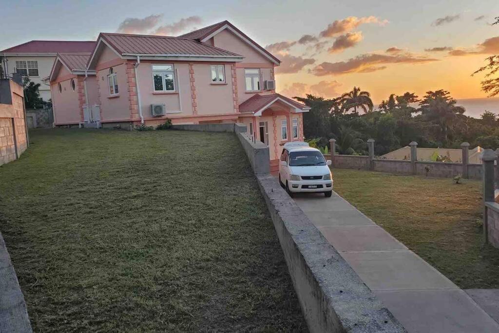 un coche aparcado frente a una casa rosa en Luxurious 4-bedroom home in serene community, en Roseau