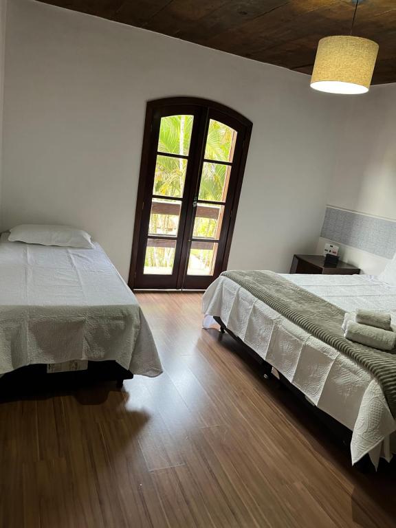 a bedroom with two beds and a window at Hostel Recanto Aurora in Petrópolis