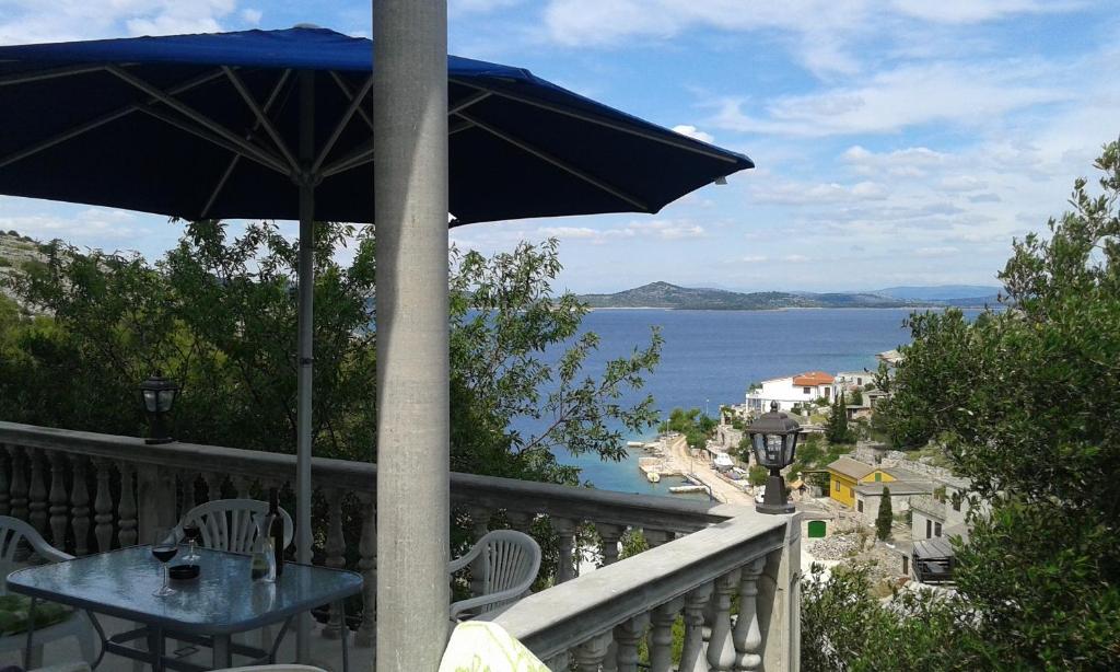 einen Tisch mit Sonnenschirm auf einem Balkon mit Blick auf das Wasser in der Unterkunft Apartment Skroza in Žirje