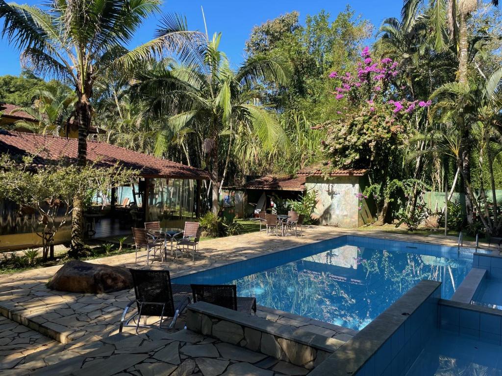 uma piscina num resort com cadeiras e árvores em Canto de Itamambuca em Ubatuba