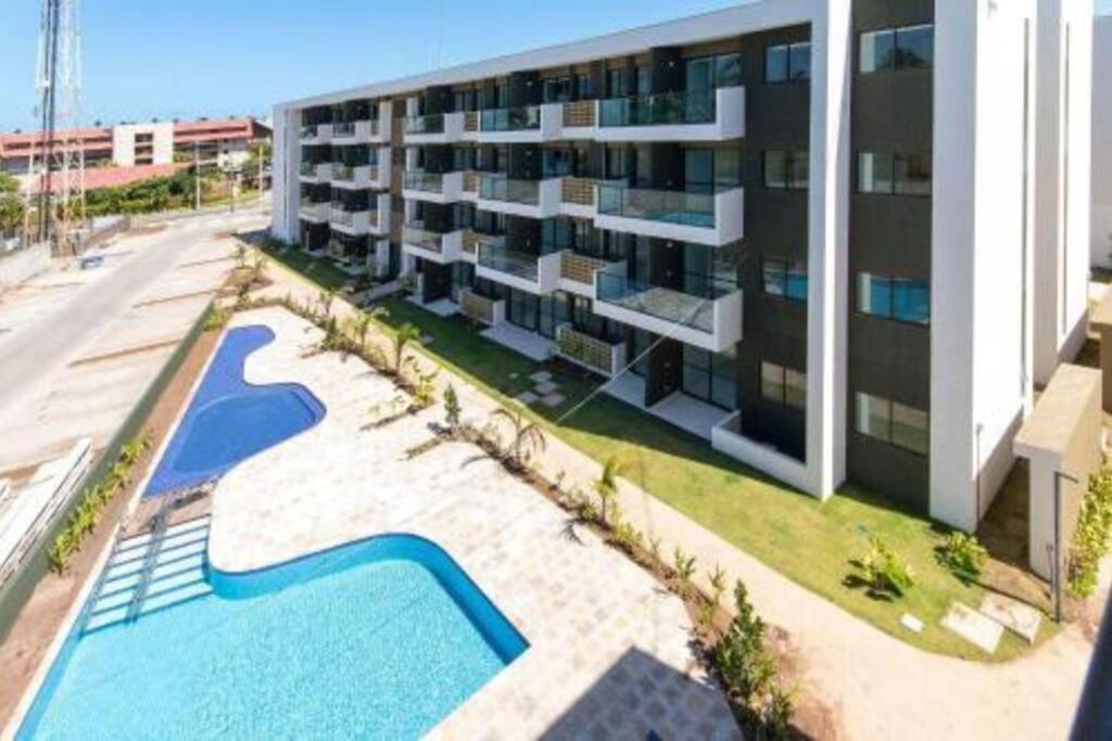 an apartment building with a swimming pool next to a building at Muro Alto - Flat Completo MANA Resort in Porto De Galinhas