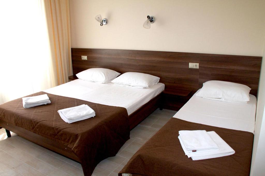 two beds in a hotel room with towels on them at Hotel Morskaya Volna in Anapa