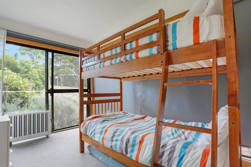 a bedroom with two bunk beds and a window at Pambula Family Beach House in Pambula Beach