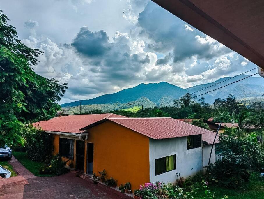 een huis met een rood dak met bergen op de achtergrond bij Spacious house, green areas, close to Río Celeste, Toucans House in Bijagua