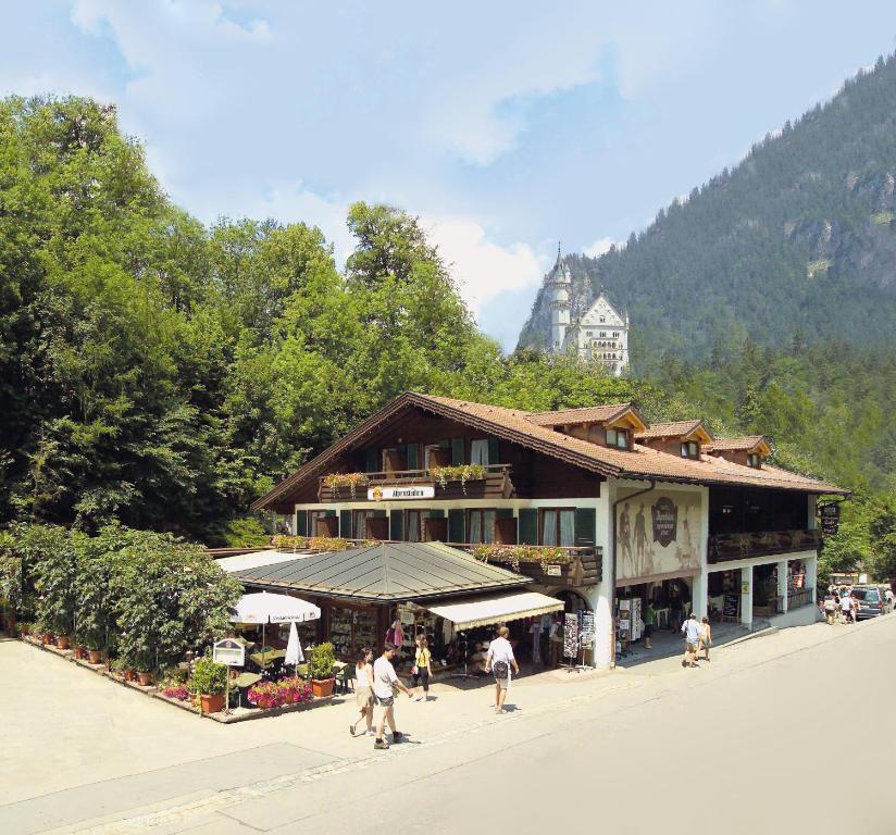 um edifício com pessoas a andar na frente dele em Hotel Alpenstuben em Hohenschwangau