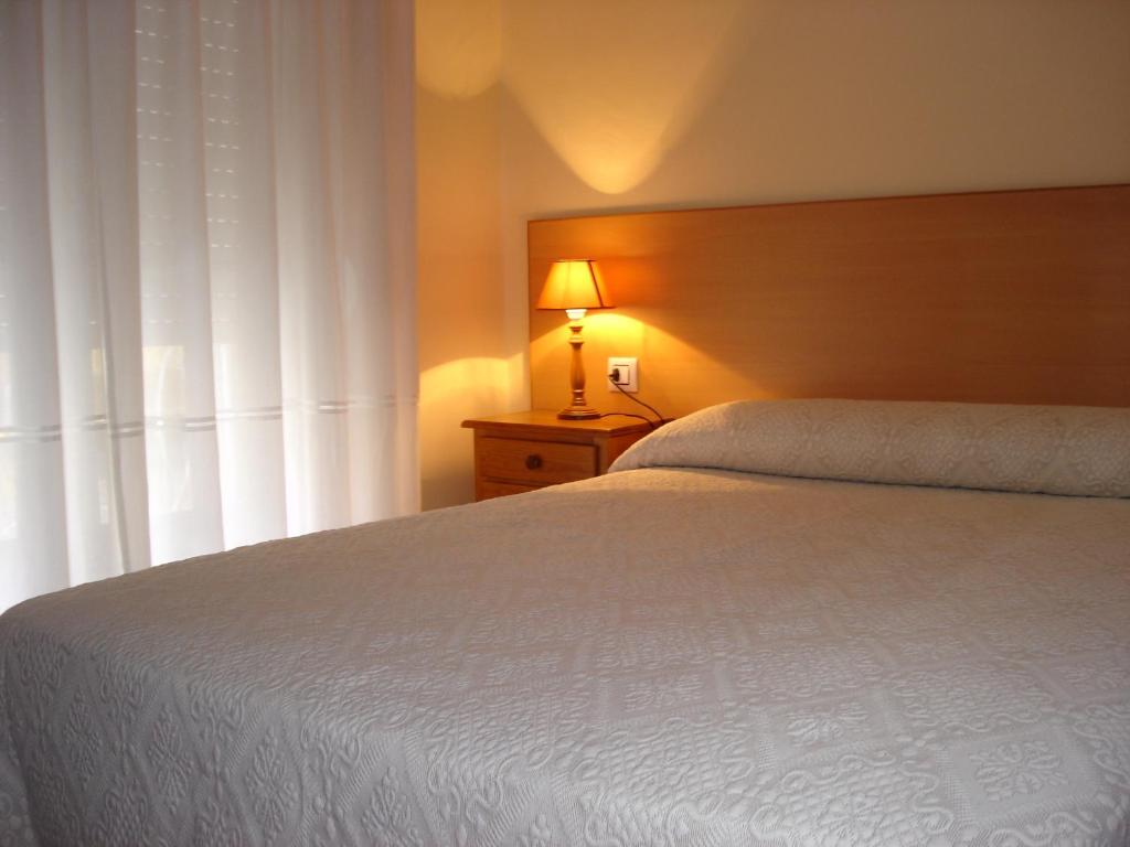 1 dormitorio con 1 cama blanca con lámpara y ventana en Pio V, en Vigo