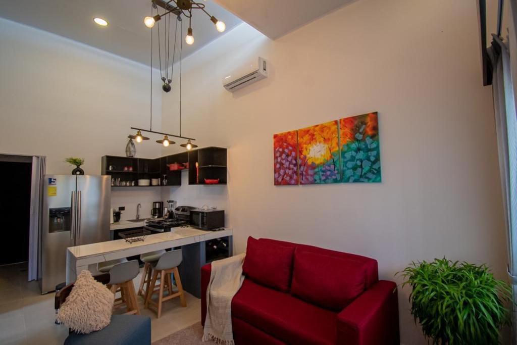 a living room with a red couch and a kitchen at Apartamentos Bukare in Quepos