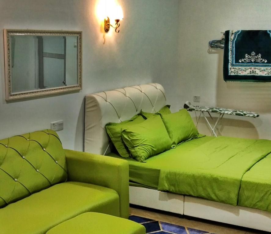 a green bed and a couch in a room at PD ROOM STAY in Port Dickson