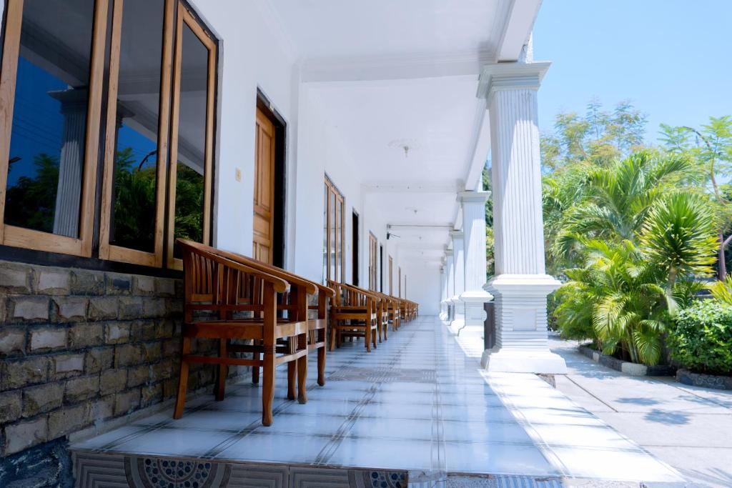 a row of benches on a building with palm trees at Hotel Green Prundi in Labuan Bajo