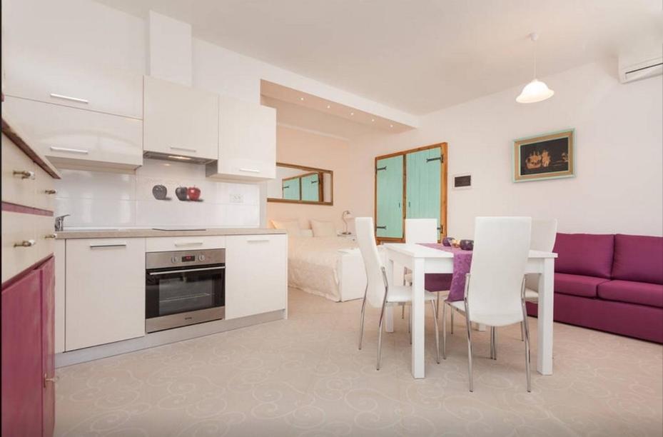 a kitchen and living room with a table and a purple couch at Studio Stella in Rovinj