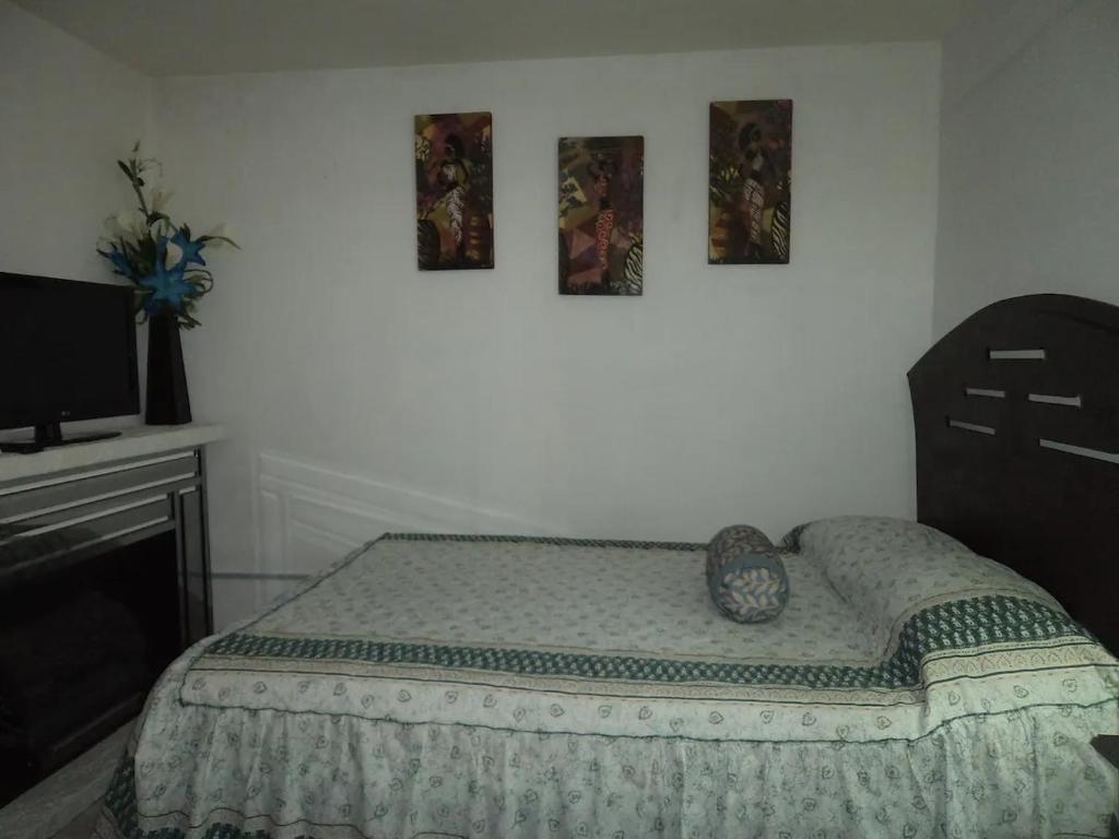 - une chambre avec un lit et deux photos sur le mur dans l'établissement Q'entiHospedaje zaguan del cielo 2, à Cusco