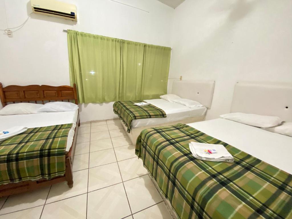 drie bedden in een kamer met groene gordijnen bij HOTEL RESTAURANT CASA DEL REY!!! in Arriaga