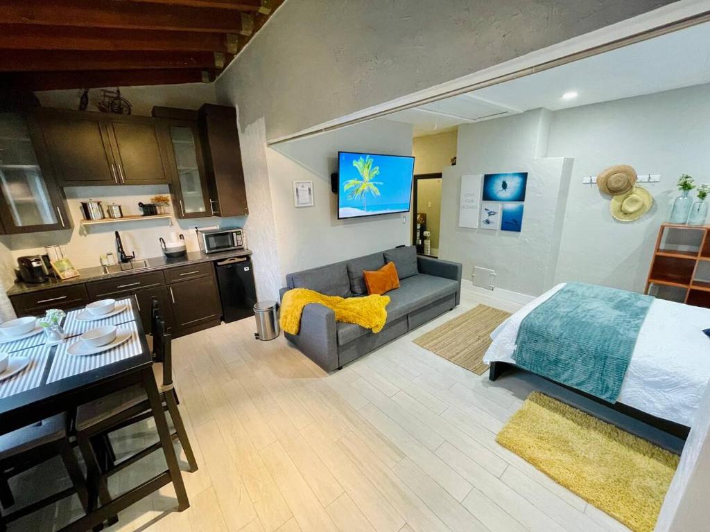 a bedroom with a bed and a couch and a kitchen at Orange You Glad you came in Miami