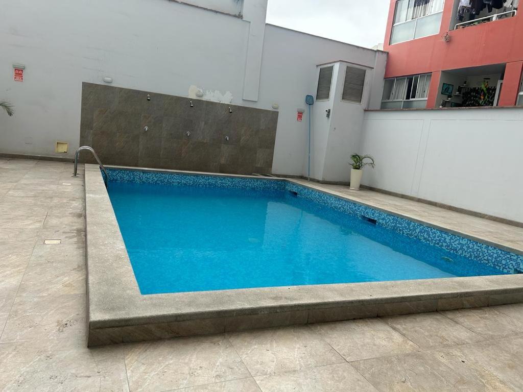a large blue swimming pool in a building at Acogedor apartamento centrico, tranquilo con piscina in Lima