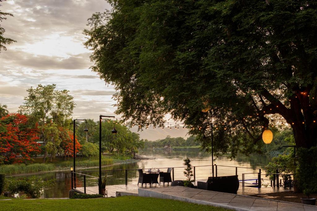 a table and chairs sitting next to a river at U Inchantree Kanchanaburi in Kanchanaburi City