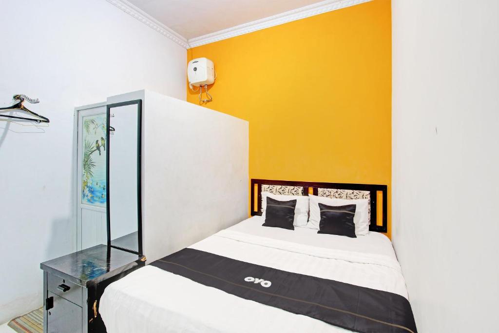 a bedroom with a bed and a yellow wall at Capital O 92929 Hotel New Tirta Kencana Syariah in Tegal