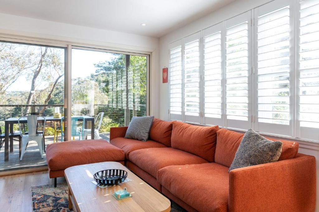 uma sala de estar com um sofá laranja e uma mesa em Katoomba Falls Cottage em Katoomba