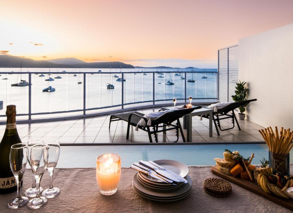 Una mesa con copas de vino y una vista de un puerto. en Penthouse Oasis On Airlie, en Airlie Beach