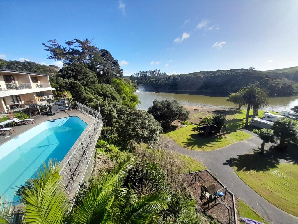 arial view of a house with a swimming pool and a river at Waterfalls Estate - Falls Motel & Waterfront Campground in Paihia