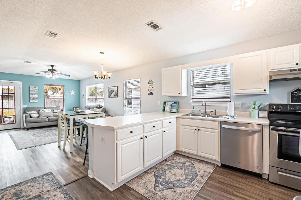 a kitchen with white cabinets and a dining room at Surfside Cottage near Navarre Beach in Navarre
