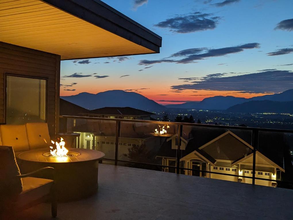 a balcony with a table and a sunset at A Mountain Retreat with Views, Hot Tub & AC in Chilliwack