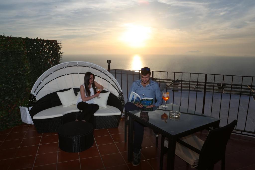a man and woman sitting on a balcony with the sunset at B&B Il Paradiso di Capri in Anacapri