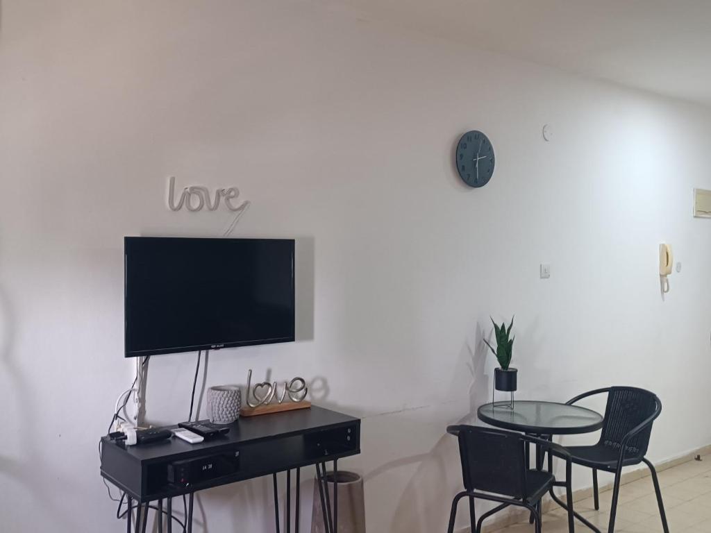 a living room with a table and a tv on a wall at דירת אירוח בית שיאים in Beer Sheva