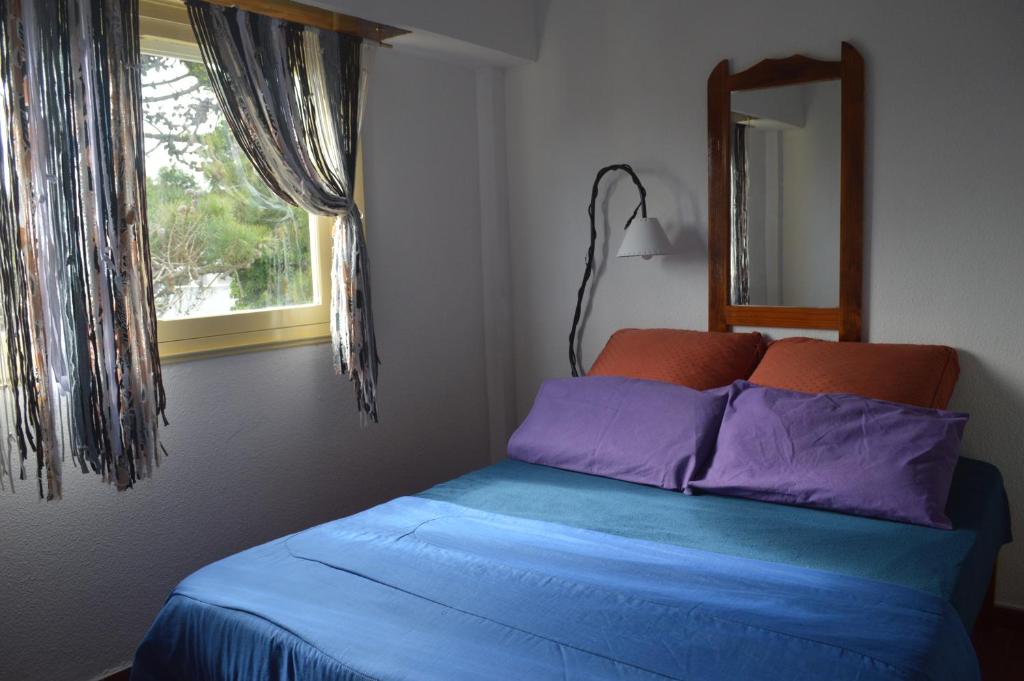 1 dormitorio con cama con espejo y ventana en Departamento en Villa Gesell en Villa Gesell