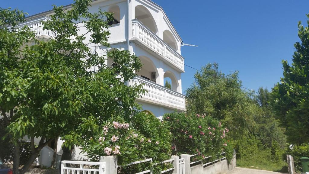 a white house with a white fence and trees at Apartment Domi in Starigrad