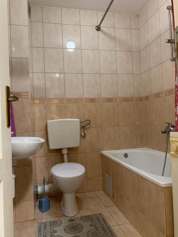 a bathroom with a toilet and a tub and a sink at Stan na dan - Apartmani Q in Doboj