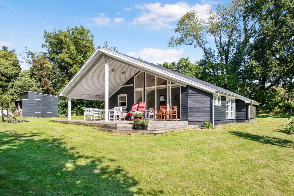 ein kleines Haus mit einer Veranda und einer Terrasse in der Unterkunft Sommerhus I Brunshuse in Hårby