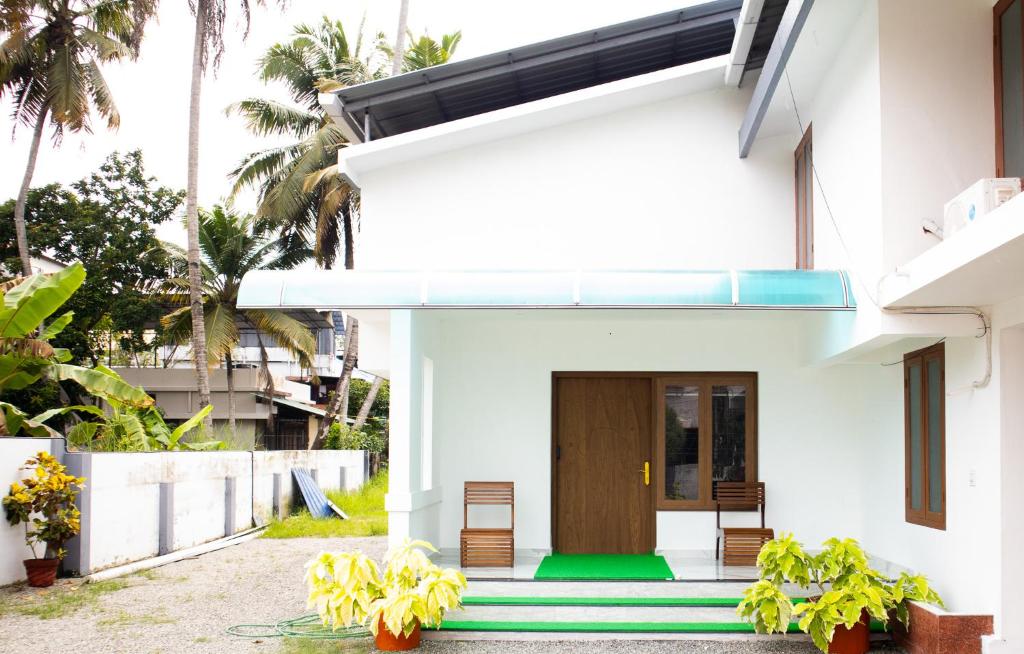 a white house with a wooden door and stairs at Salalah Enclave - 3 AC Bedroom House at Vytilla, Kochi in Cochin