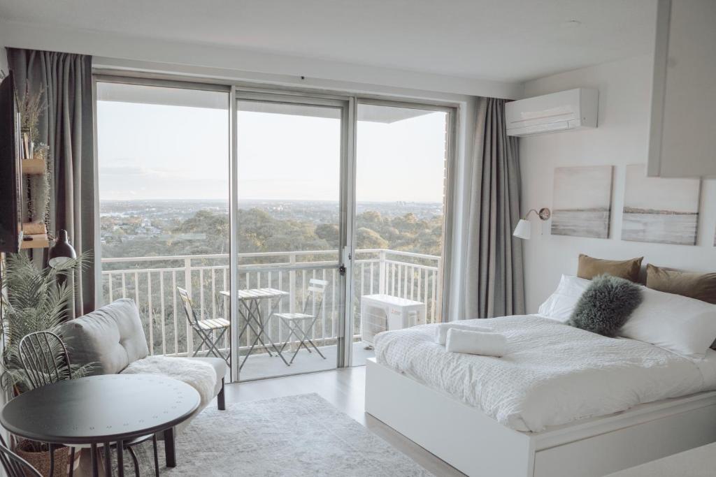 a bedroom with a bed and a balcony with a table at Cosy studio with a big view in Sydney