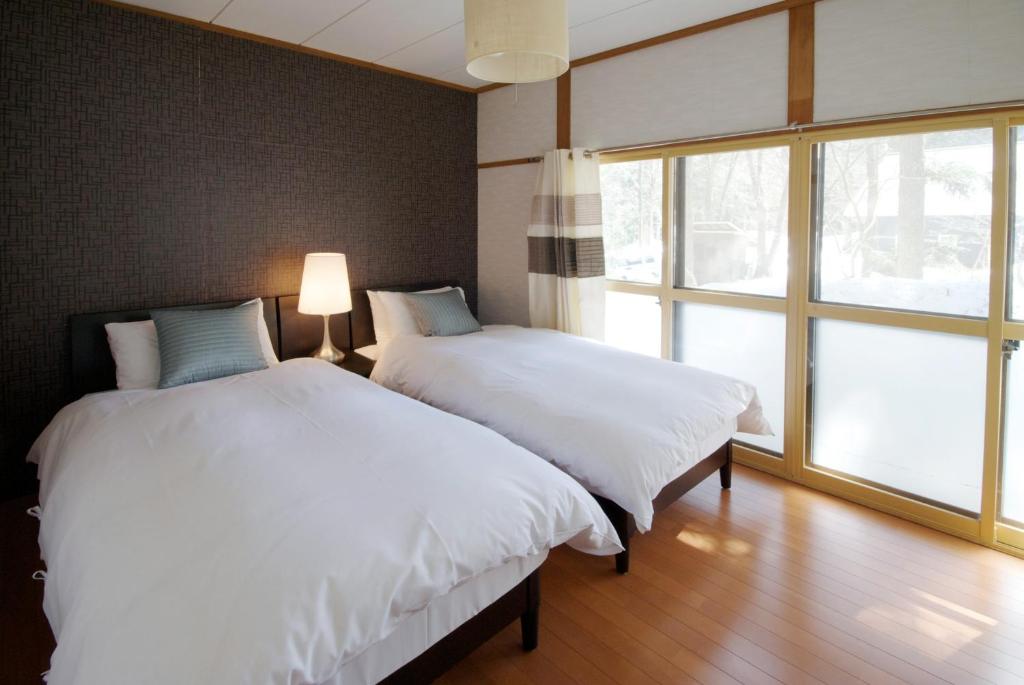 two beds in a room with a window at Hakuba Forest House in Hakuba