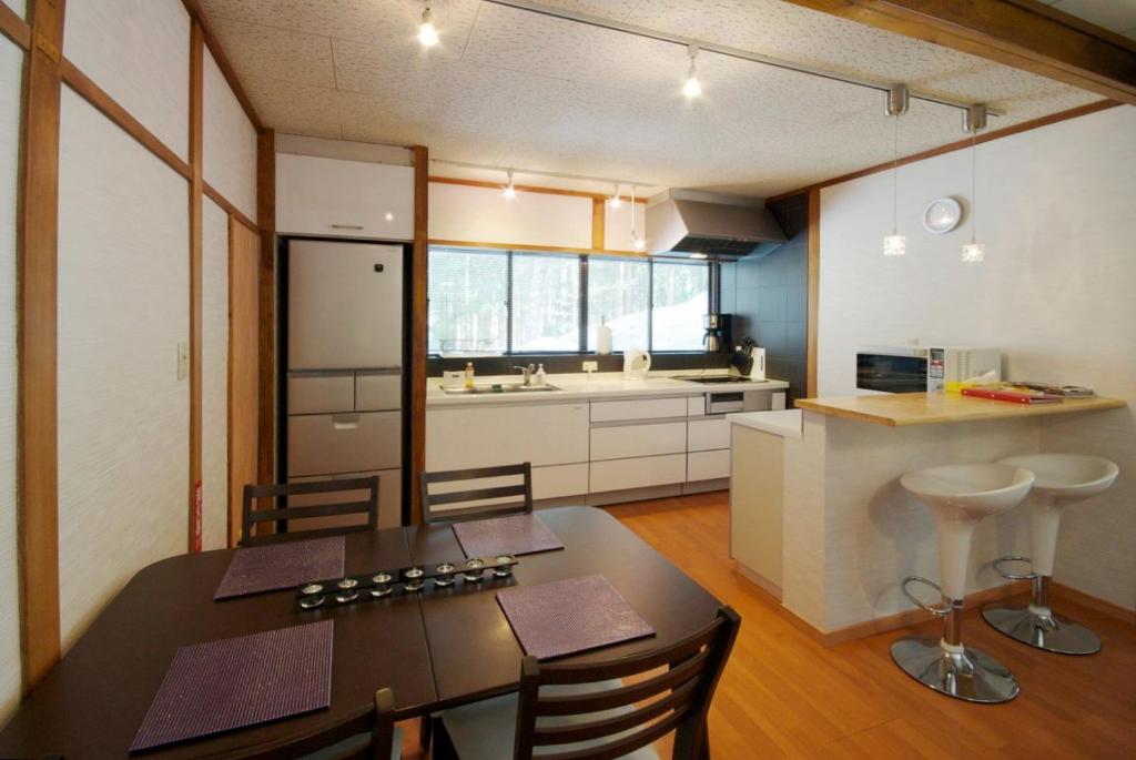 a kitchen with a dining table and a kitchen with a counter at Hakuba Forest House in Hakuba