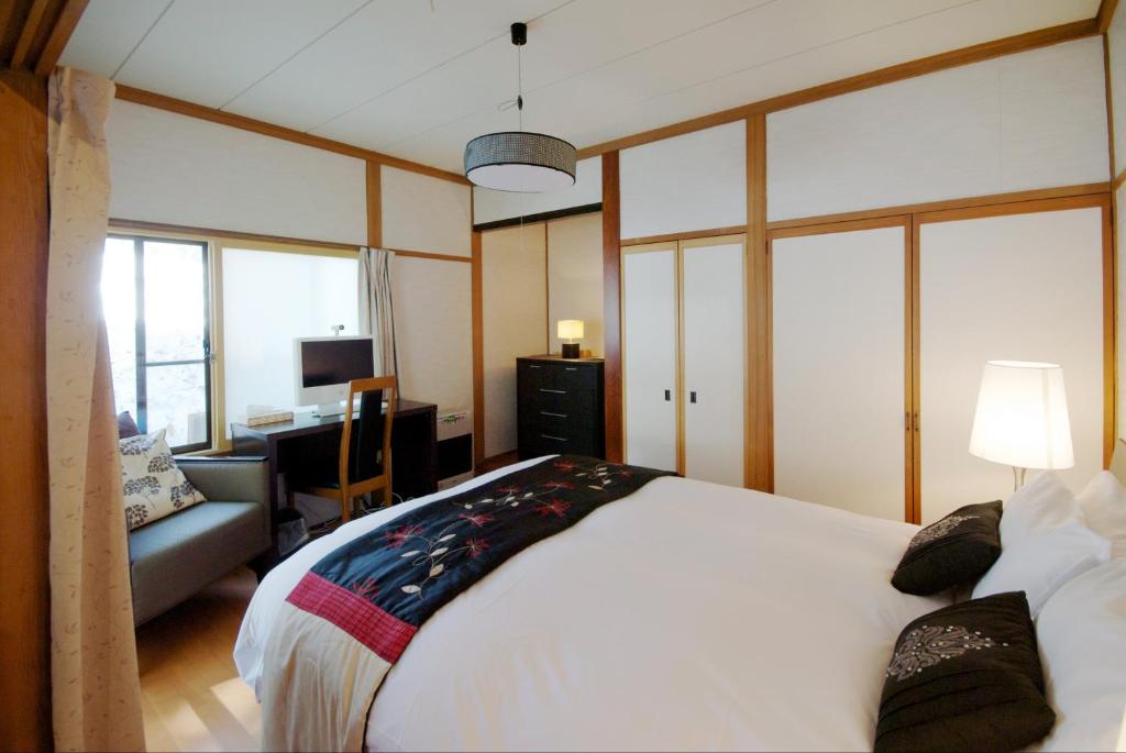 a bedroom with a large white bed and a desk at Hakuba Forest House in Hakuba