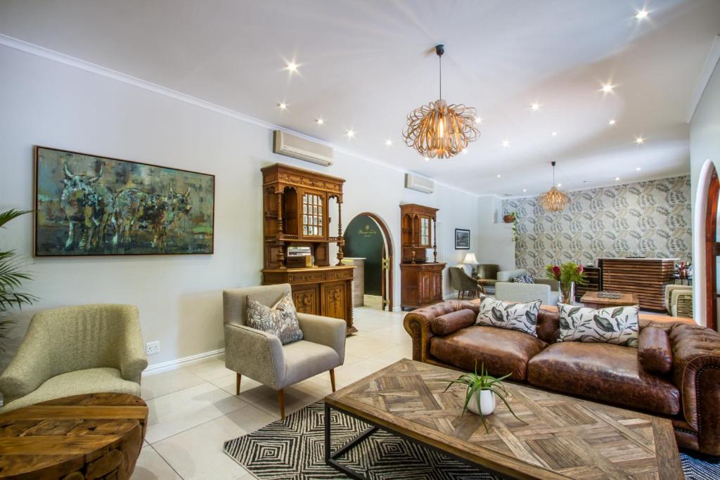 a living room with a couch and chairs and a table at Hlangana Lodge in Oudtshoorn