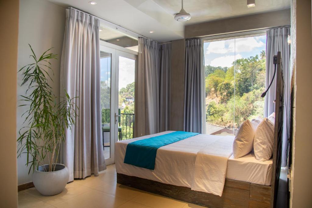 um quarto com uma cama e uma grande janela em Kurumbunkz em Kandy
